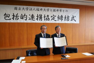 協定書を手にする坂本憲男市長（左）と眞弓光文学長（右）